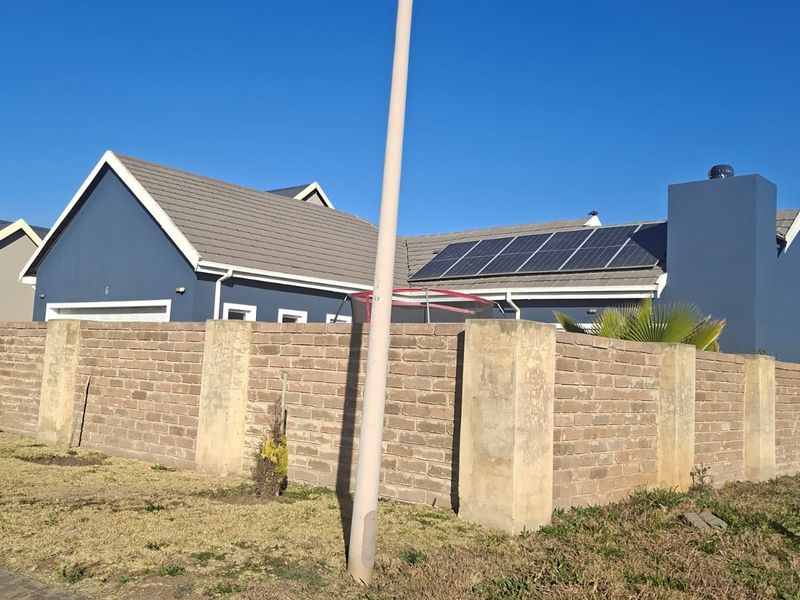 Front view of a residential property featuring a brick boundary wall, tiled roof, and installed solar panels.