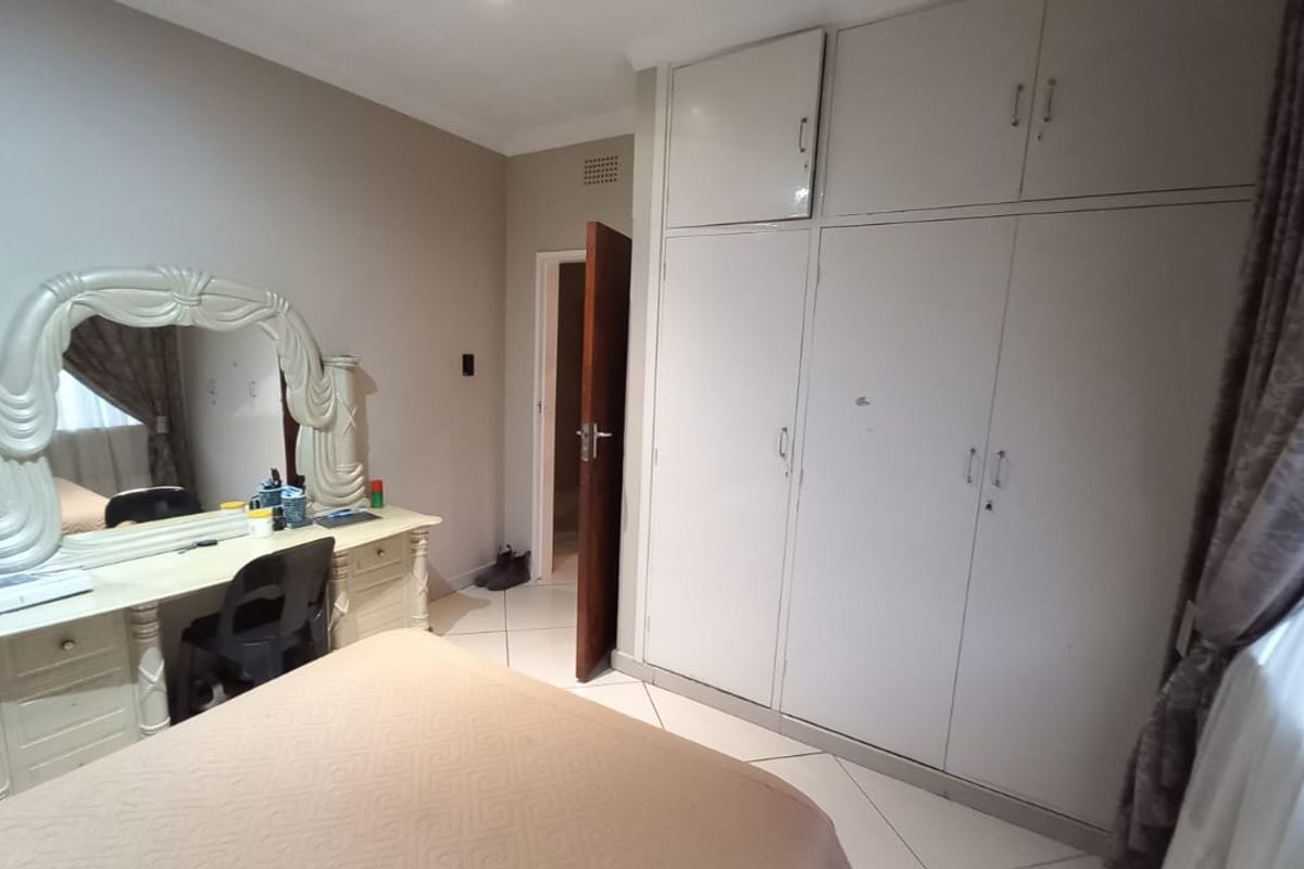 A bedroom featuring built-in cupboards and tiled flooring, offering a functional space with potential for cosmetic updates to modernize the finishes.