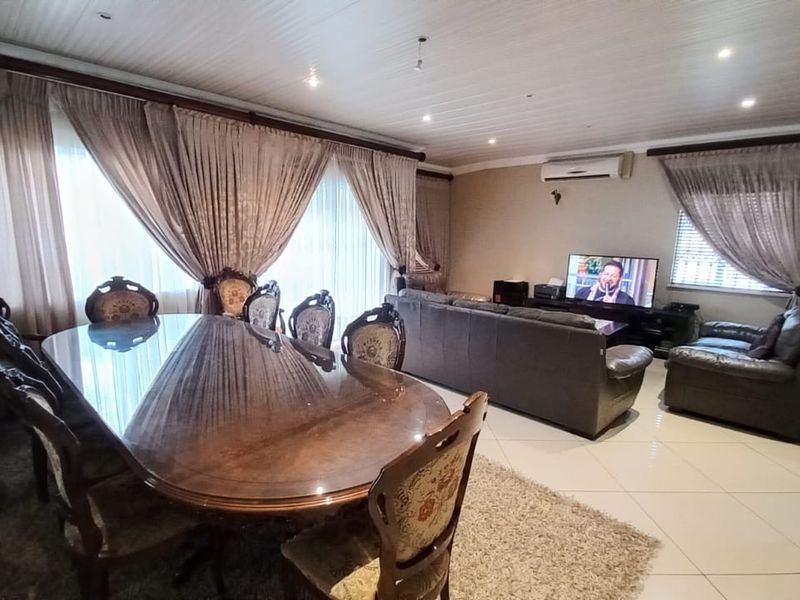 Spacious open-plan living and dining area featuring tiled flooring, recessed lighting, and a wall-mounted air conditioning unit.