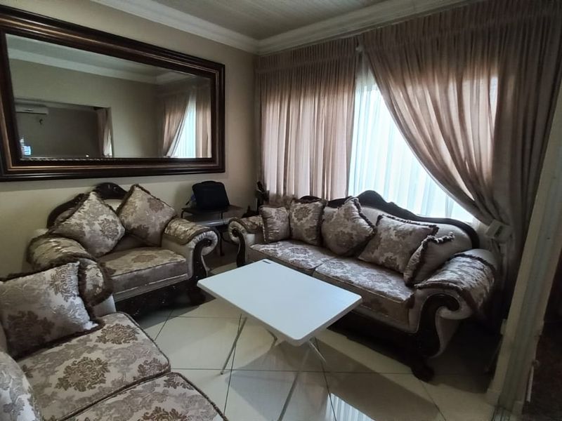 A living room featuring tiled flooring, crown molding, and a large decorative wall mirror.