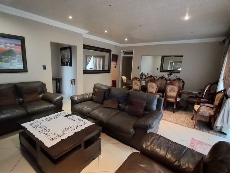 Spacious open-plan living and dining area featuring tiled flooring, recessed lighting, and decorative coved cornicing, providing a versatile layout for family living.