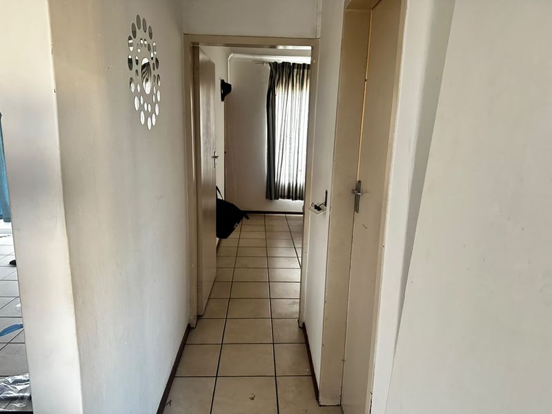 A functional hallway featuring tiled flooring and access to adjacent rooms, requiring minor cosmetic updates to improve its overall appearance.