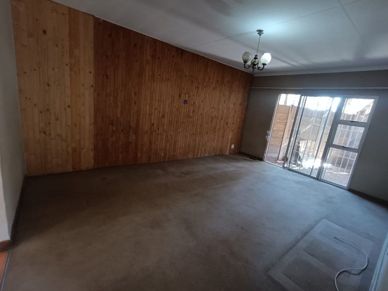 Spacious living area featuring wood paneling, carpet flooring, and a sliding glass door providing access to the exterior.