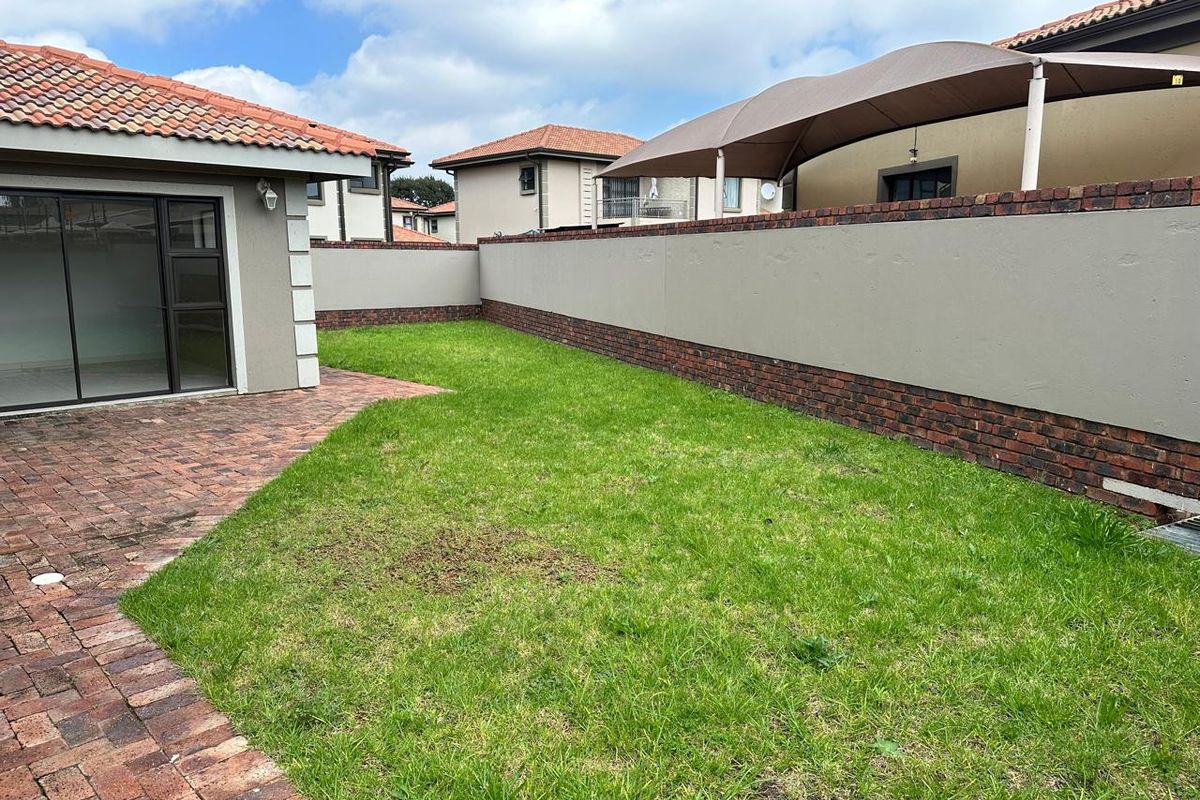 A private rear garden featuring a brick-paved patio area, a well-maintained lawn, and a secure perimeter boundary wall.