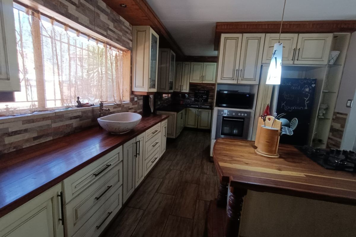 A rustic-style kitchen featuring timber benchtops, a unique vessel sink, built-in oven, gas cooktop, and warm timber-look flooring.