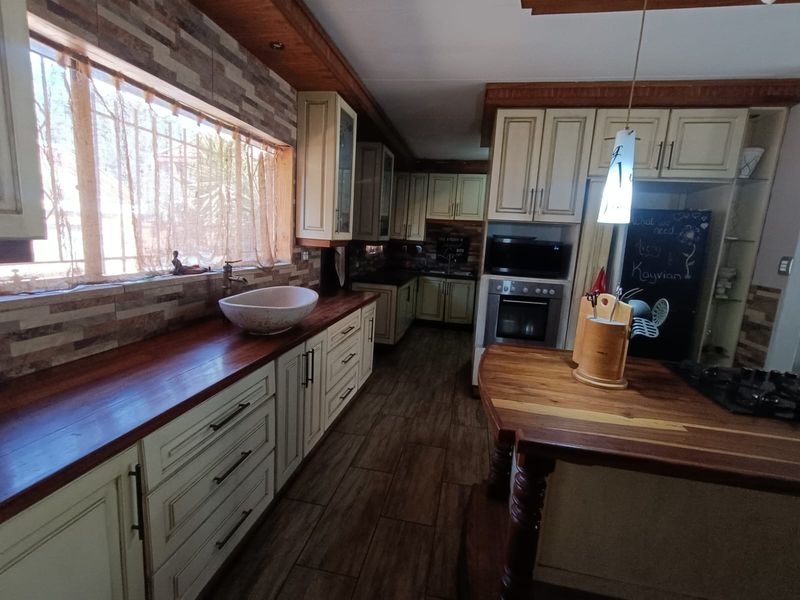A rustic-style kitchen featuring timber benchtops, a unique vessel sink, built-in oven, gas cooktop, and warm timber-look flooring.