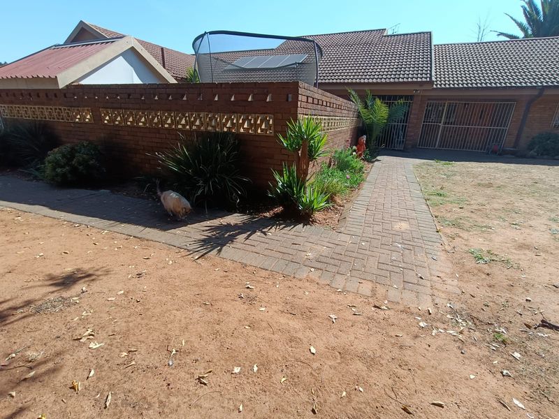 Front exterior view of the property featuring a brick boundary wall with decorative breeze blocks, a paved walkway, and a tiled roof structure.