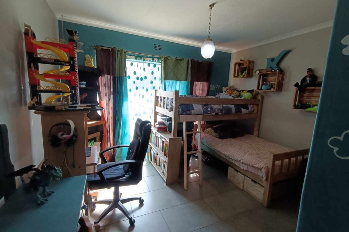 A functional bedroom featuring tiled flooring, a central pendant light, and access to an outdoor area via a sliding door.