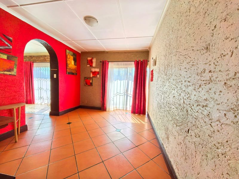 A spacious living area featuring tiled flooring, a distinctive arched doorway, and a sliding glass door providing access to the exterior.