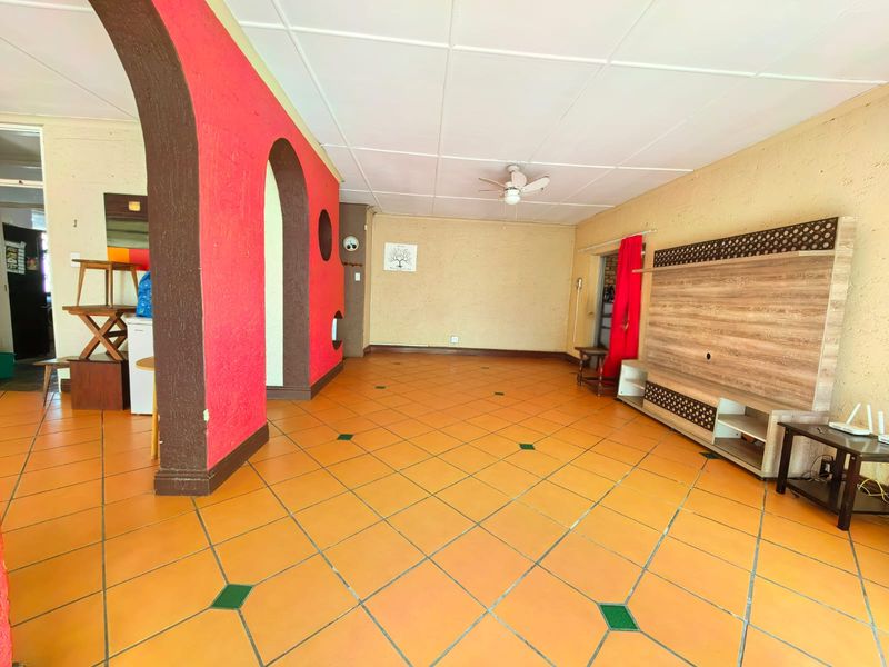 Spacious living area featuring distinctive decorative archways, tiled flooring, and a built-in media unit, offering a versatile layout for comfortable family living.