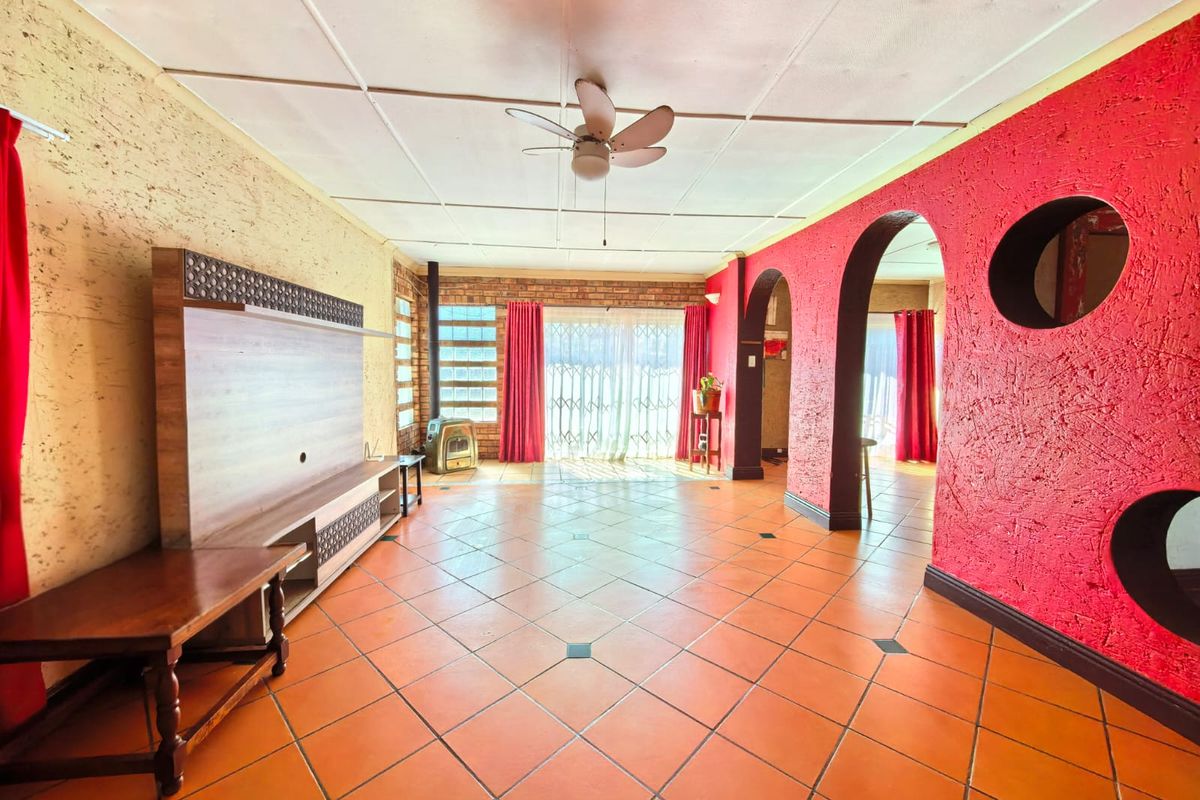 Spacious living area featuring terracotta tiled floors, a brick feature wall, a freestanding fireplace, and distinctive arched architectural details.