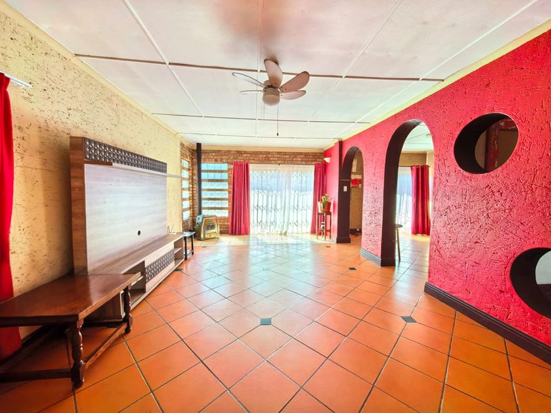 Spacious living area featuring terracotta tiled floors, a brick feature wall, a freestanding fireplace, and distinctive arched architectural details.