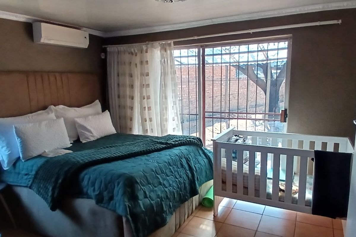 A bedroom featuring tiled flooring, crown molding, an air conditioning unit, and a sliding glass door with security bars leading to the exterior.