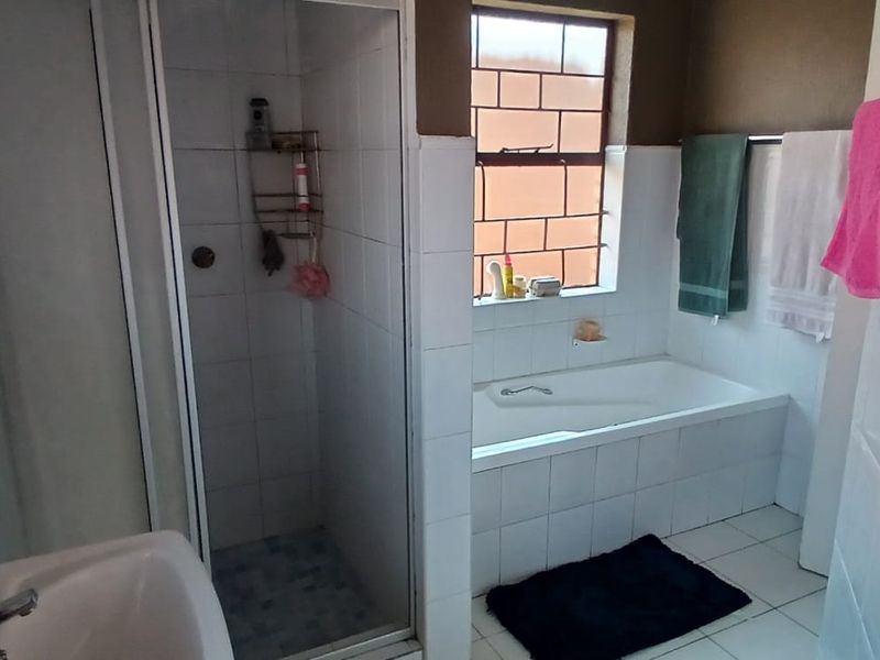 A functional bathroom featuring a separate shower enclosure, a built-in bathtub, and tiled finishes throughout.