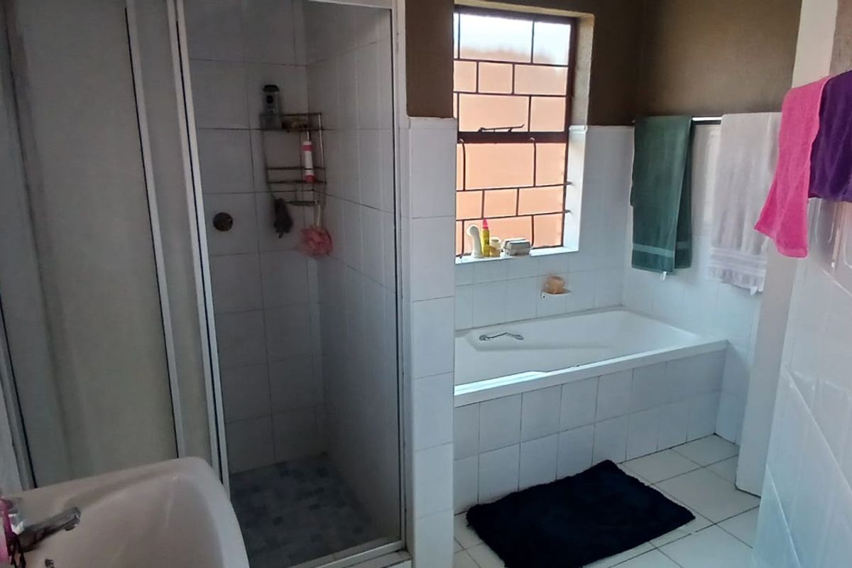 A functional bathroom featuring a separate shower enclosure, a built-in bathtub, and tiled finishes throughout.