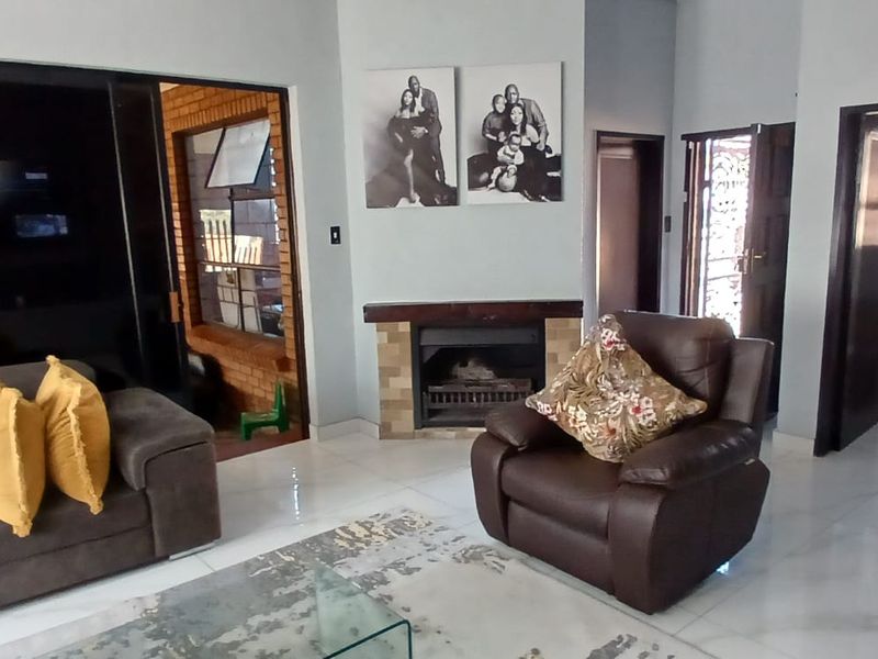 Living room featuring a built-in fireplace, tiled flooring, and access to adjacent rooms and outdoor areas.