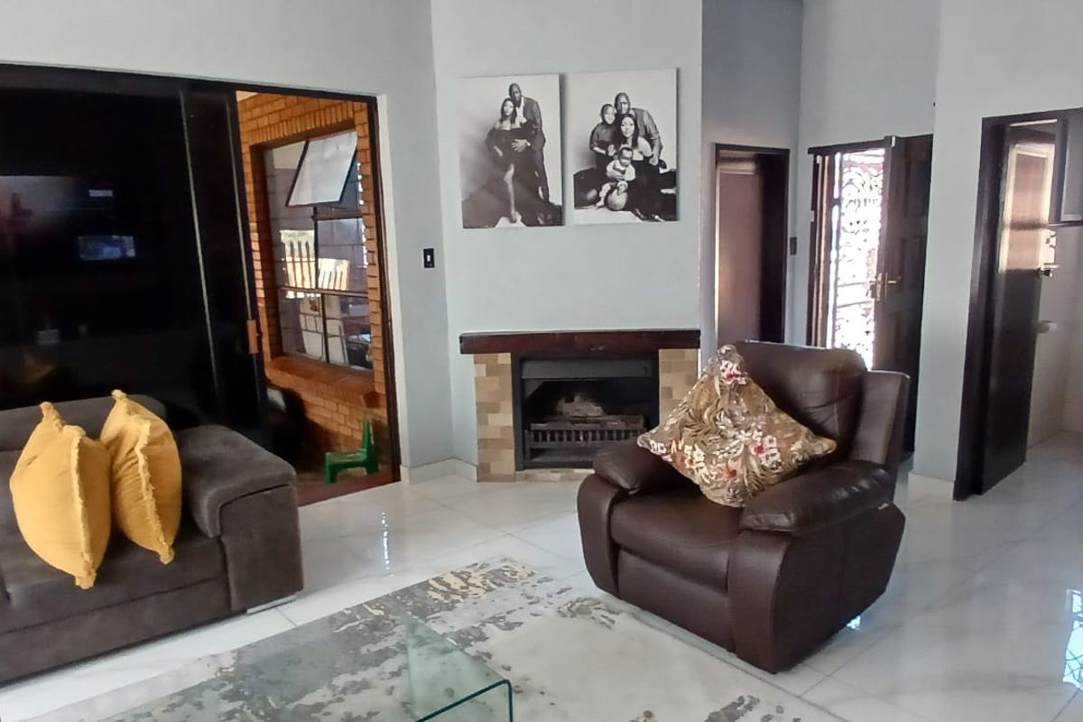 Living room featuring a built-in fireplace, tiled flooring, and access to adjacent rooms and outdoor areas.