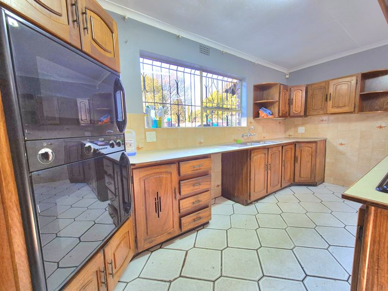 Functional kitchen featuring traditional wooden cabinetry, a double wall oven, tiled backsplash, and hexagonal floor tiles with security bars on the window.