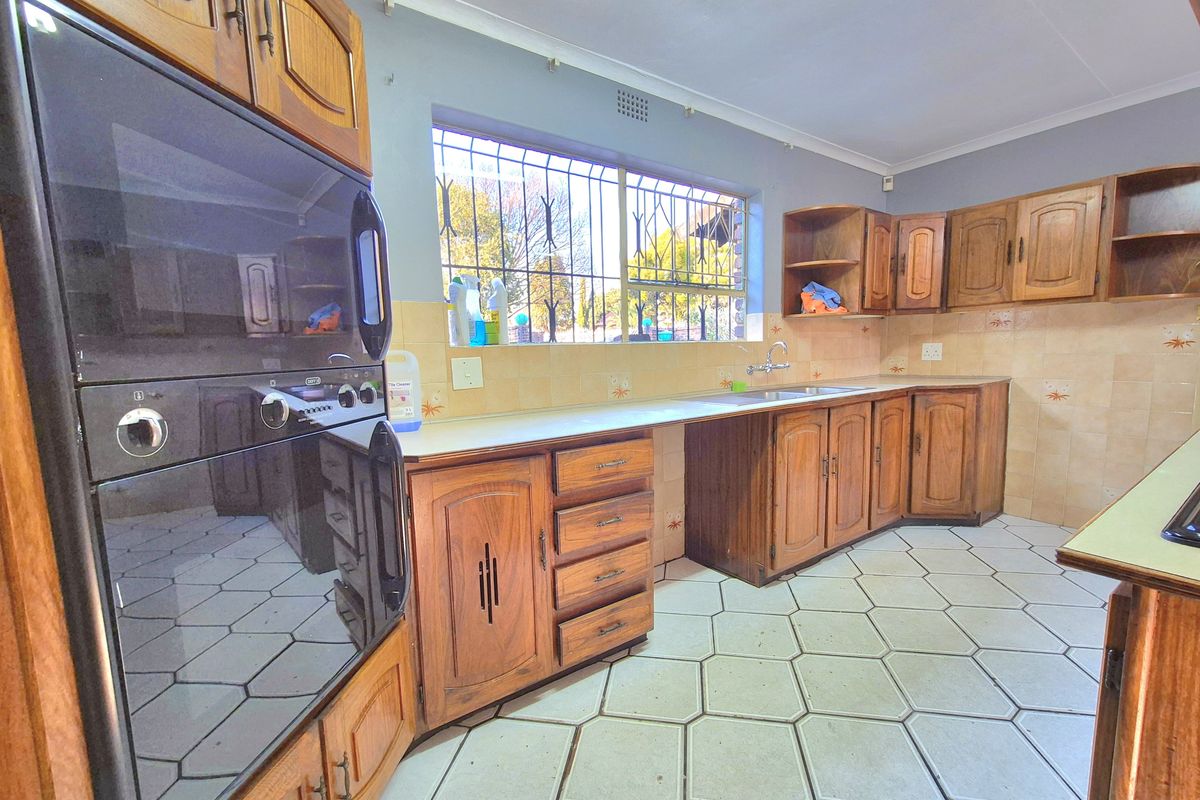 Functional kitchen featuring traditional wooden cabinetry, a double wall oven, tiled backsplash, and hexagonal floor tiles with security bars on the window.