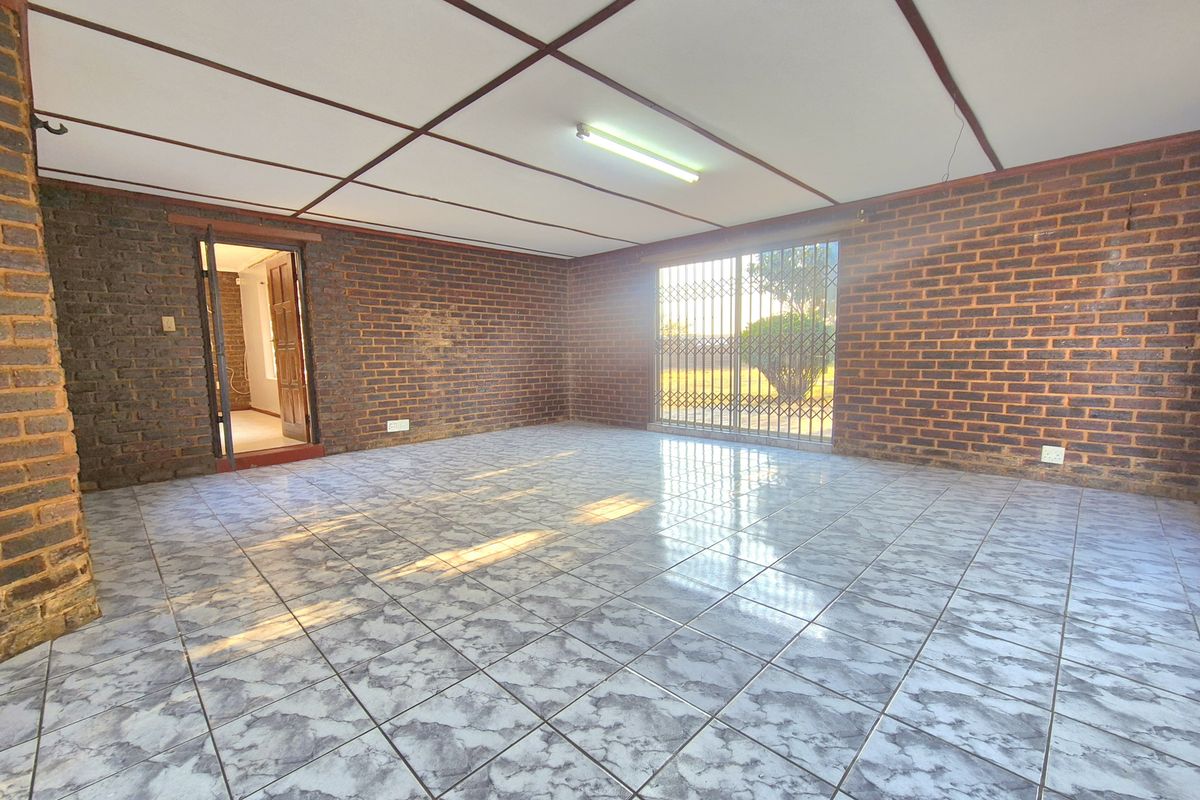 Spacious living area featuring exposed brick walls, tiled flooring, and a security gate leading to the exterior.