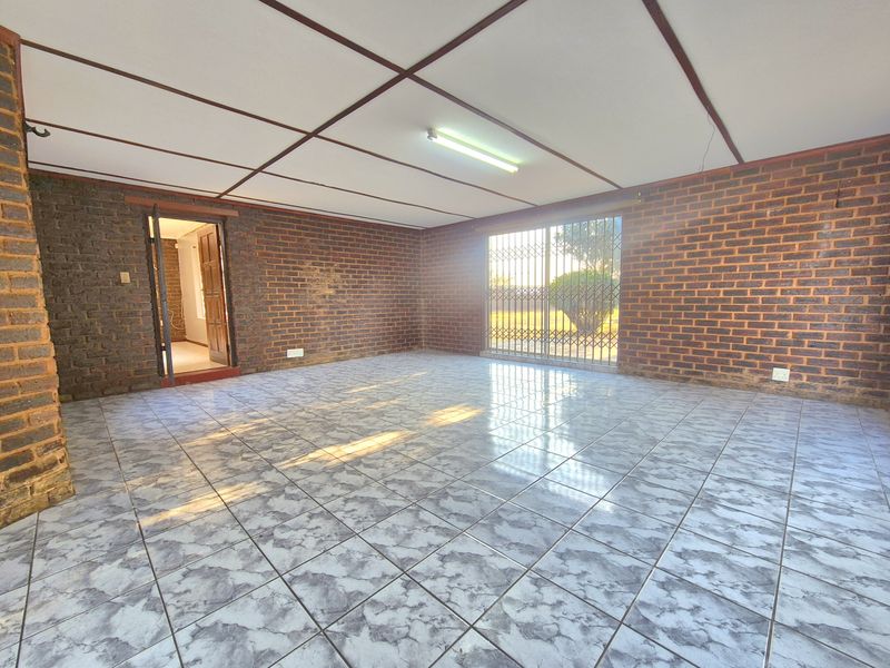 Spacious living area featuring exposed brick walls, tiled flooring, and a security gate leading to the exterior.