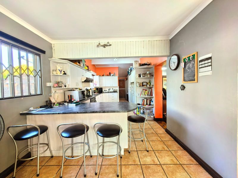 A functional kitchen featuring a breakfast bar, built-in cabinetry, and tiled flooring, offering a practical layout with potential for modern cosmetic updates.