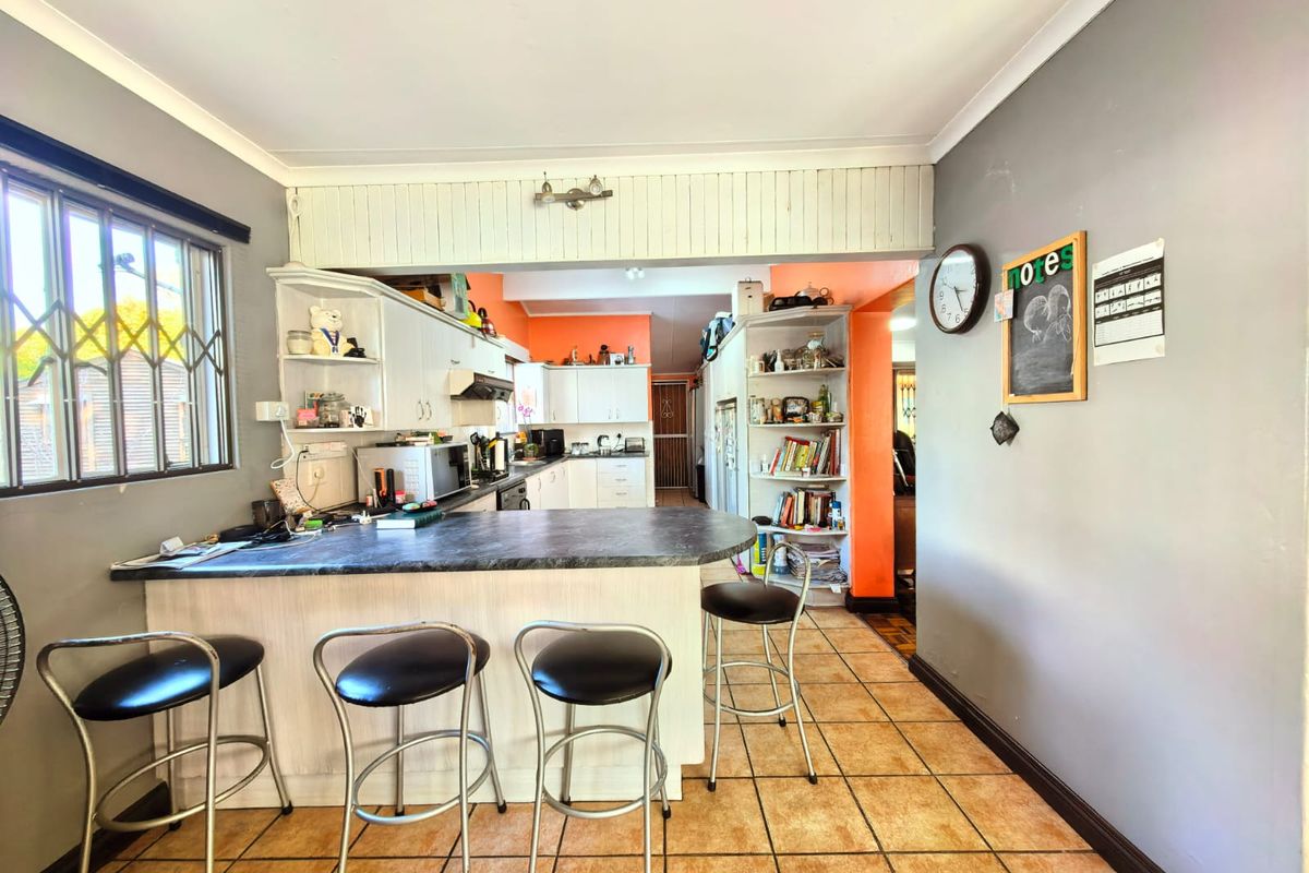 A functional kitchen featuring a breakfast bar, built-in cabinetry, and tiled flooring, offering a practical layout with potential for modern cosmetic updates.