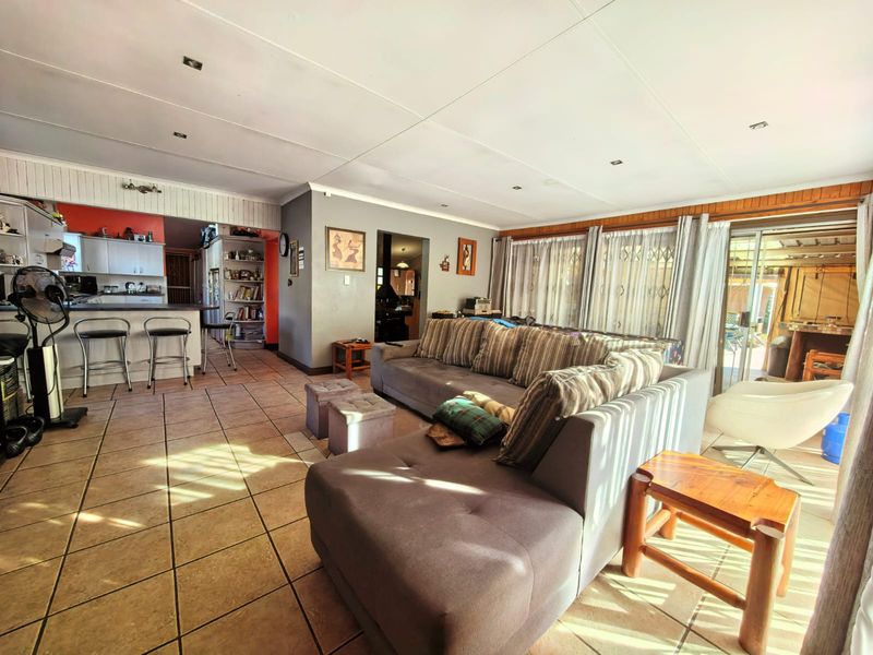 Spacious open-plan living area featuring tiled flooring, recessed lighting, and a breakfast bar, with direct access to the outdoor patio through sliding glass doors.
