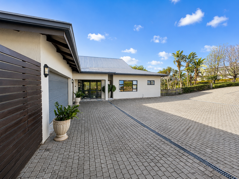 Front exterior view of the property featuring a spacious paved driveway, garage access, and modern architectural finishes with a clean, well-maintained facade.