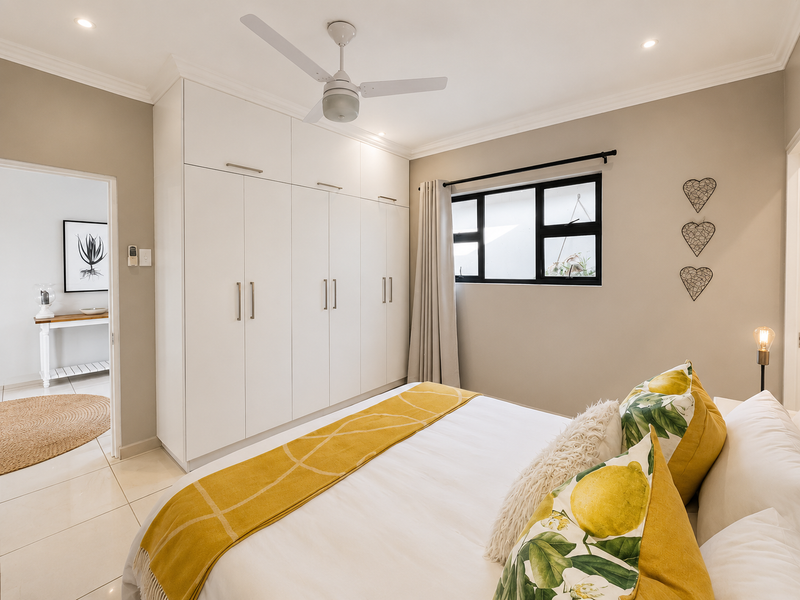A well-maintained bedroom featuring built-in floor-to-ceiling cupboards, modern tiled flooring, a ceiling fan, and recessed lighting with neutral wall finishes.