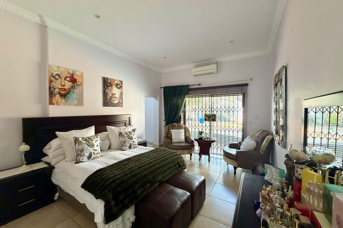 Spacious bedroom featuring tiled flooring, a split-system air conditioner, and a sliding door with a security gate leading to the exterior.