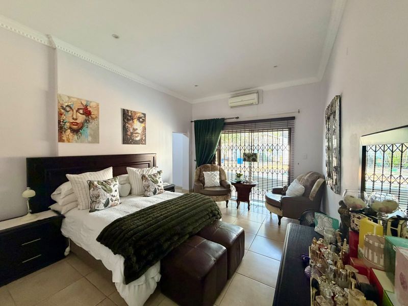 Spacious bedroom featuring tiled flooring, a split-system air conditioner, and a sliding door with a security gate leading to the exterior.