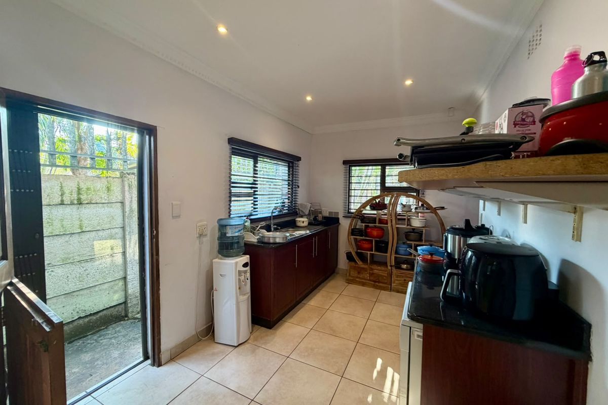 Functional kitchen featuring dark wood cabinetry, granite countertops, tiled flooring, and direct access to an outdoor area.