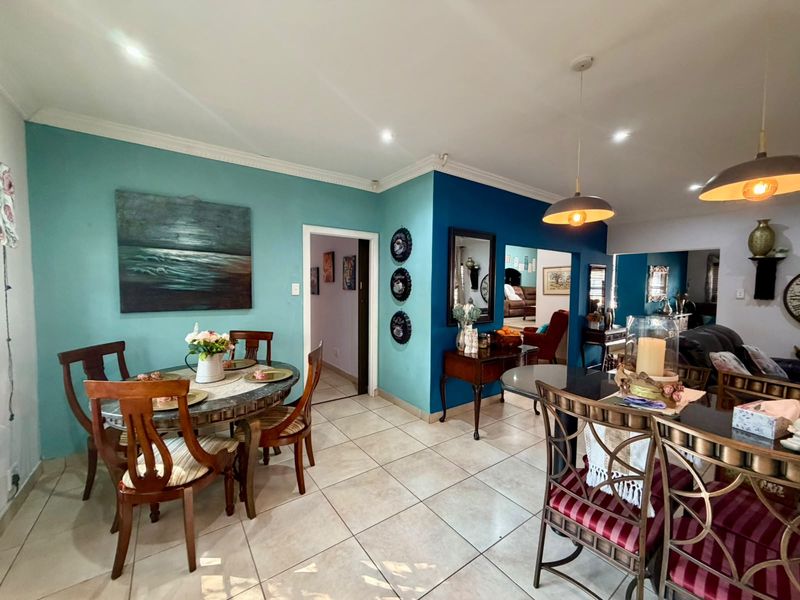 Open plan dining and living area featuring ceramic floor tiles, recessed downlighting, and bold accent walls.
