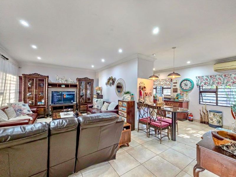 Spacious open-plan living and dining area featuring tiled flooring, recessed downlighting, and a wall-mounted air conditioning unit.