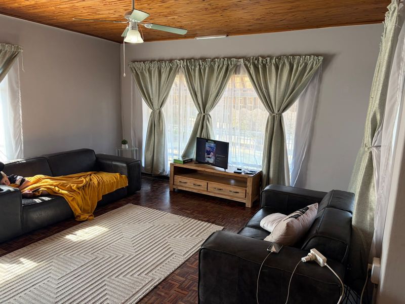 A living room featuring warm timber ceilings, a ceiling fan, and classic parquet flooring, providing a comfortable and inviting space.