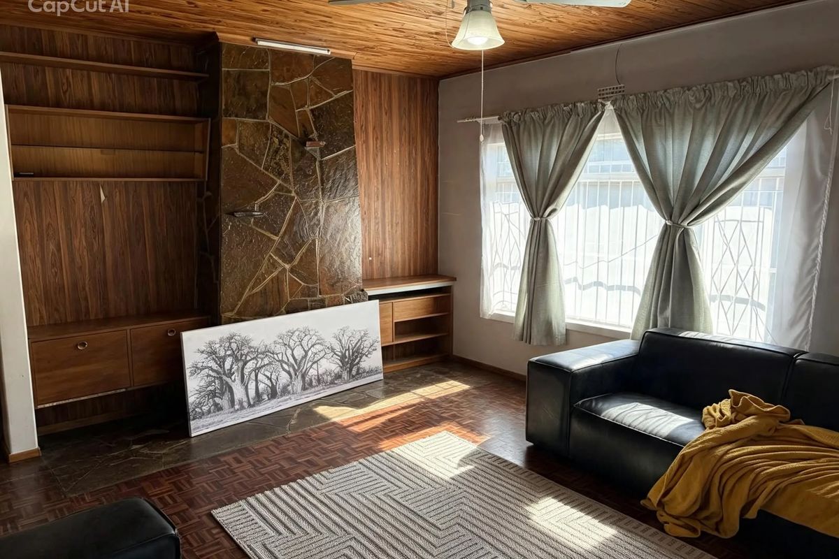 Living room featuring a stone fireplace, timber ceiling, built-in wooden cabinetry, and parquet flooring, offering a classic, dated aesthetic ready for modernization.