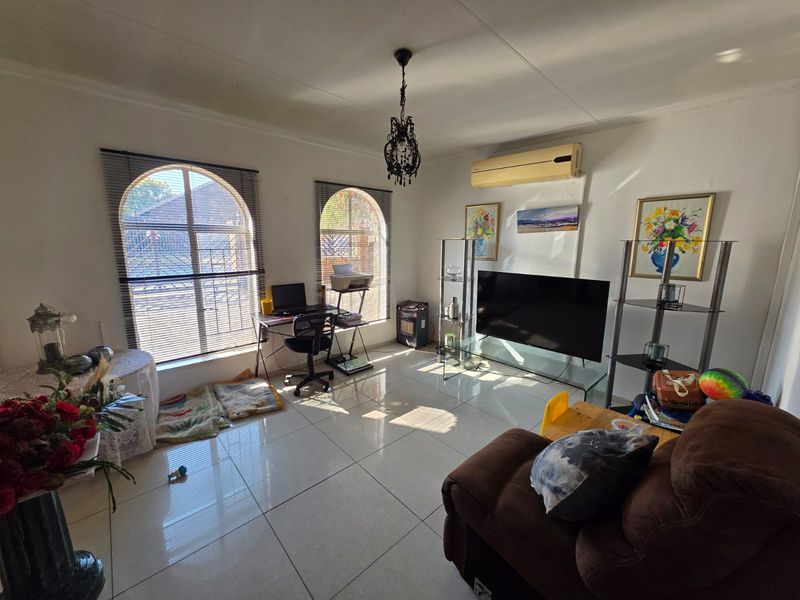 A bright living room featuring large arched windows, polished tiled flooring, and a wall-mounted air conditioning unit.