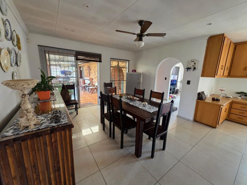 Open-plan dining area featuring tiled flooring, a ceiling fan, and an arched transition to the living space, with direct access to the patio.