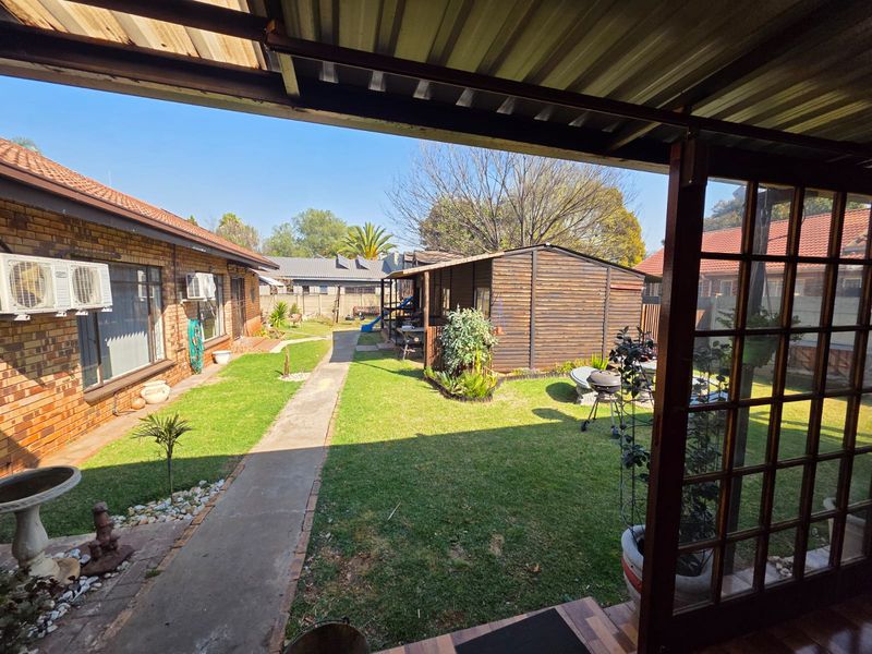 A covered patio area overlooking a well-maintained garden with a concrete pathway and a detached timber garden shed.