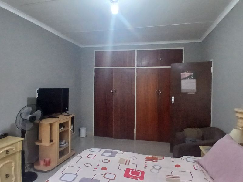 A bedroom featuring built-in wooden cupboards and neutral wall finishes, providing a functional space with ample storage.
