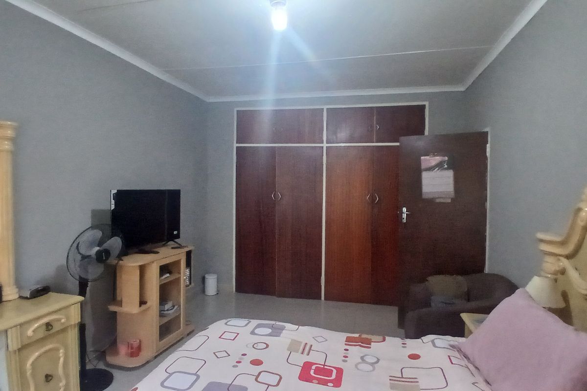 A bedroom featuring built-in wooden cupboards and neutral wall finishes, providing a functional space with ample storage.