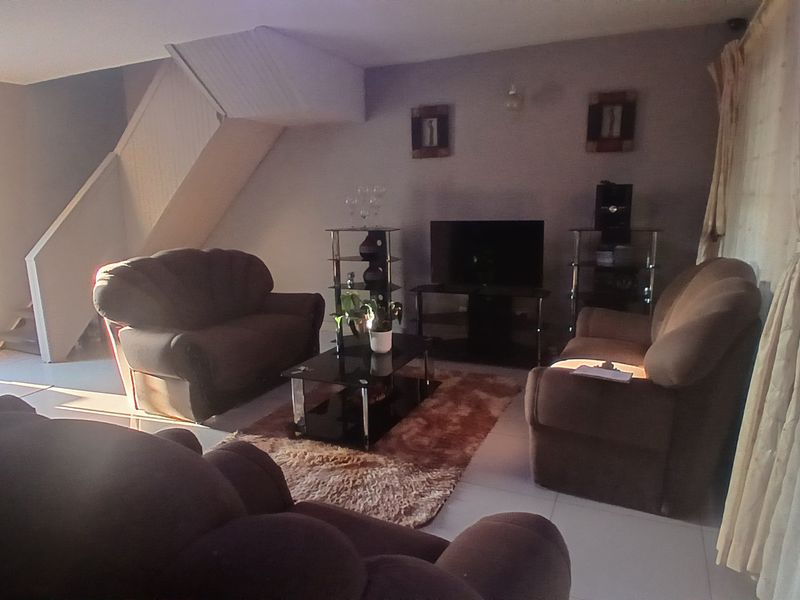 A living room area featuring tiled flooring and an integrated staircase leading to the upper level.