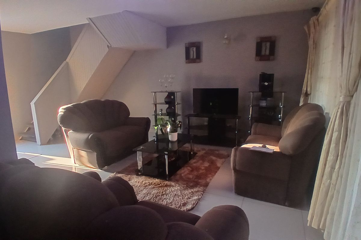 A living room area featuring tiled flooring and an integrated staircase leading to the upper level.