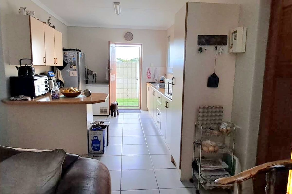 A functional kitchen featuring laminate cabinetry, tiled flooring, and direct access to the rear exterior area.