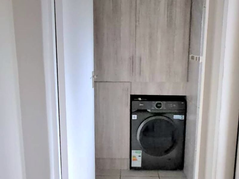 A compact laundry area featuring built-in cabinetry and tiled flooring, providing functional storage and space for a washing machine.