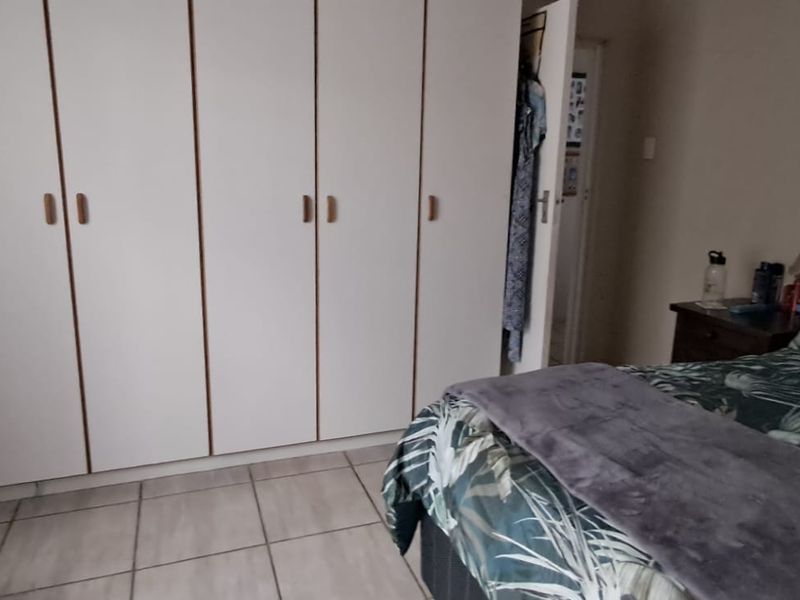 A bedroom featuring tiled flooring and a large wall-to-wall built-in cupboard unit.