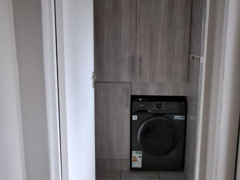 A compact laundry area featuring built-in cabinetry and tiled flooring, providing functional storage and utility space.
