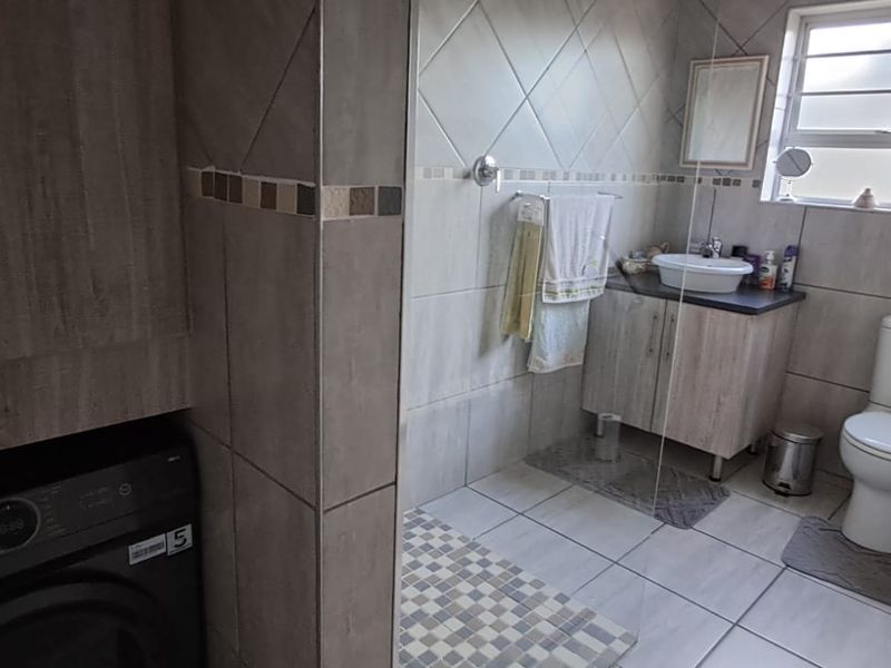 A functional bathroom featuring tiled finishes, a vanity with a vessel sink, a toilet, and integrated cabinetry for storage.