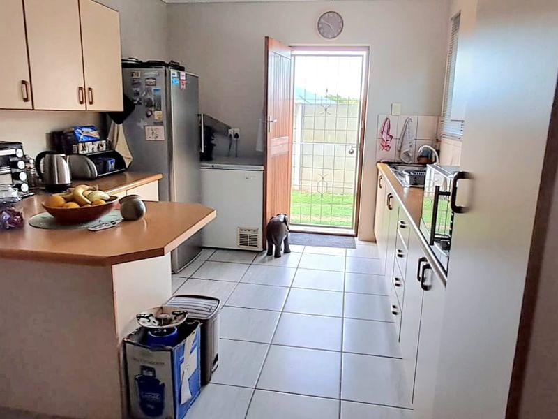 Functional kitchen featuring laminate countertops, built-in cabinetry, and tiled flooring with direct access to the exterior through a security gate.